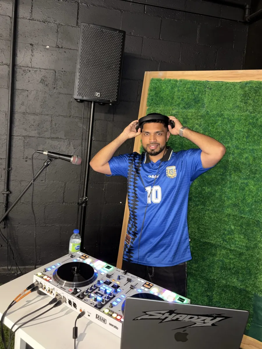 DJ Shadzy in the studio wearing headphones, Shadzy logo on his laptop