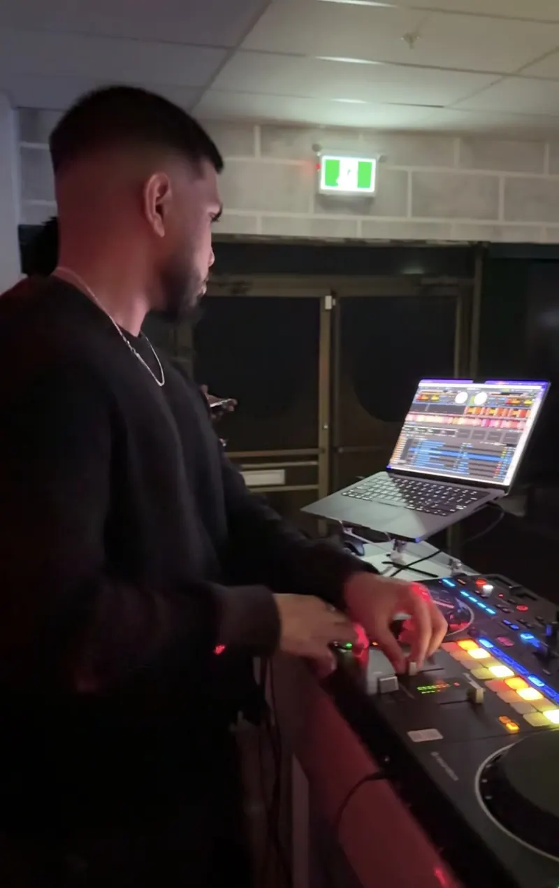 DJ Shadzy mixing in a dark venue, lit by the controller's pads