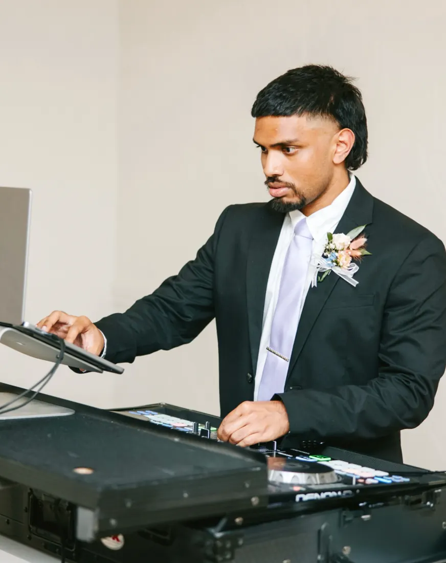 DJ Shadzy in a suit and boutonniere at the decks during a wedding